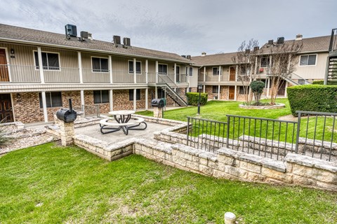 the backyard of an apartment building with a fire pit